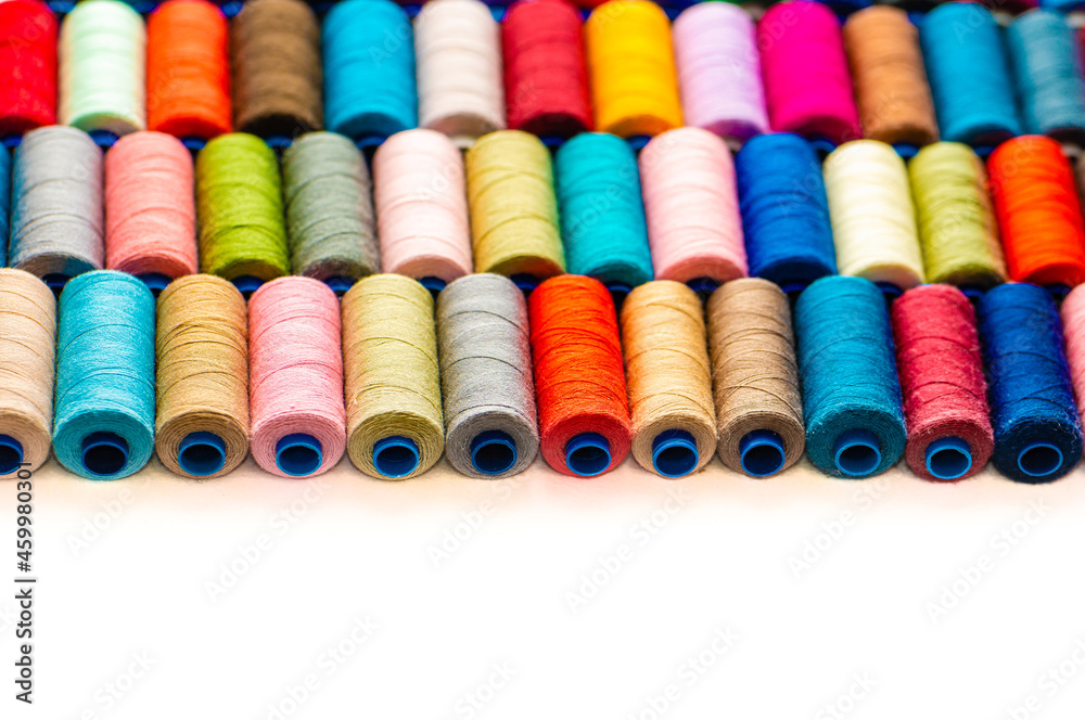 Multi-colored sewing threads laid out in a row. Bright background. Multi-colored sewing threads laid out in a row. Bright background.
