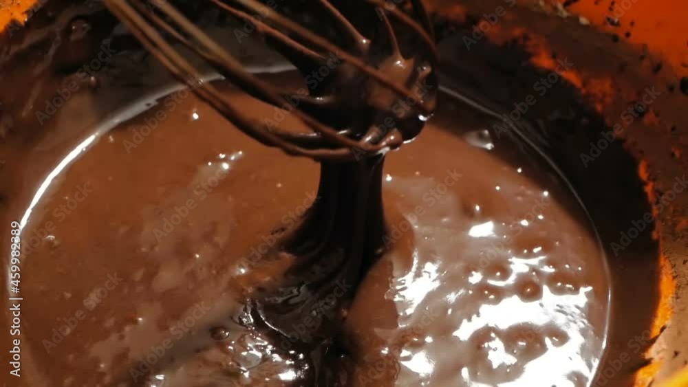 The chef mixes the chocolate with a blender, preparing the ingredients for the cake. The chef mixes the chocolate cream for the cake with a mixer.