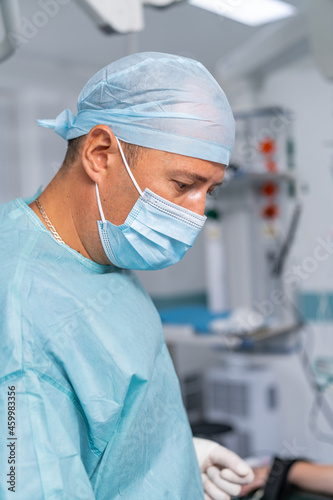 Portrait of professional surgeon with medical equipment. Confident surgery doctor operating in medical mask