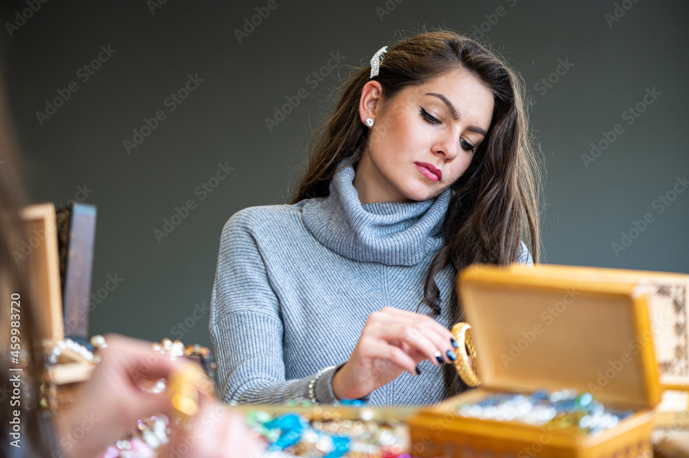Fototapeta premium reflection of a woman in mirror choosing and trying different jewelry, soft focus, closeup