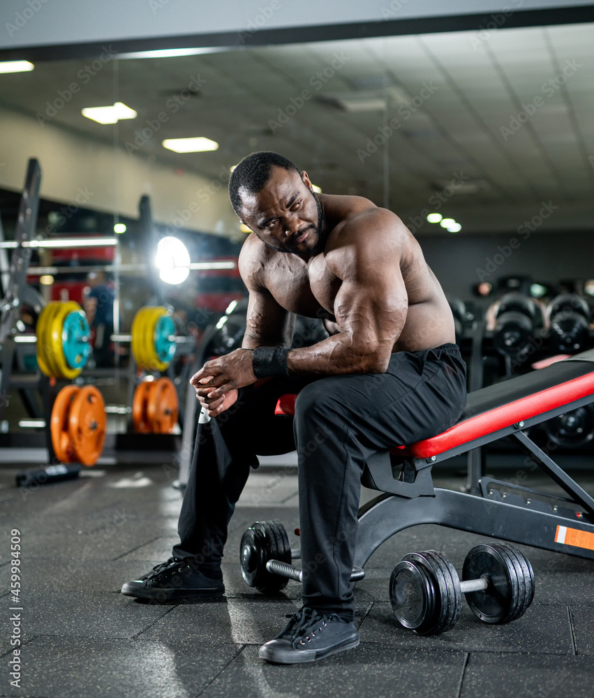 Fototapeta premium Handsome muscular bodybuilder have a rest after training. Shirtless strong man resting after an active workout