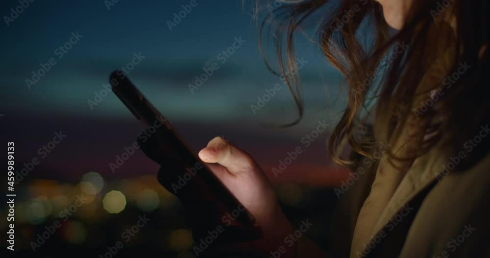 Close up on person use smartphone in sunset on street. Millennial generation z female scroll through news feed on app on her phone. Cinematic film look photo of pretty woman at sunset use phone