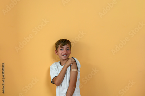 Smiling teenage boy shows a band aid on his arm. Vaccine concept