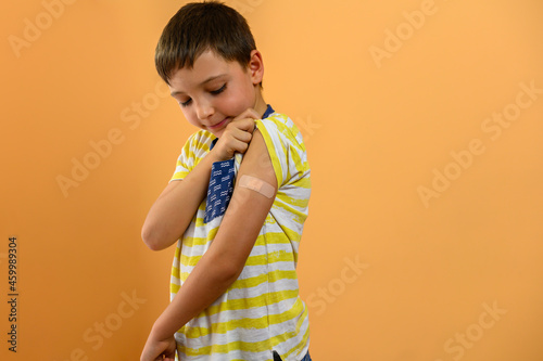 A child looks at a band aid on his arm. Vaccine concept
