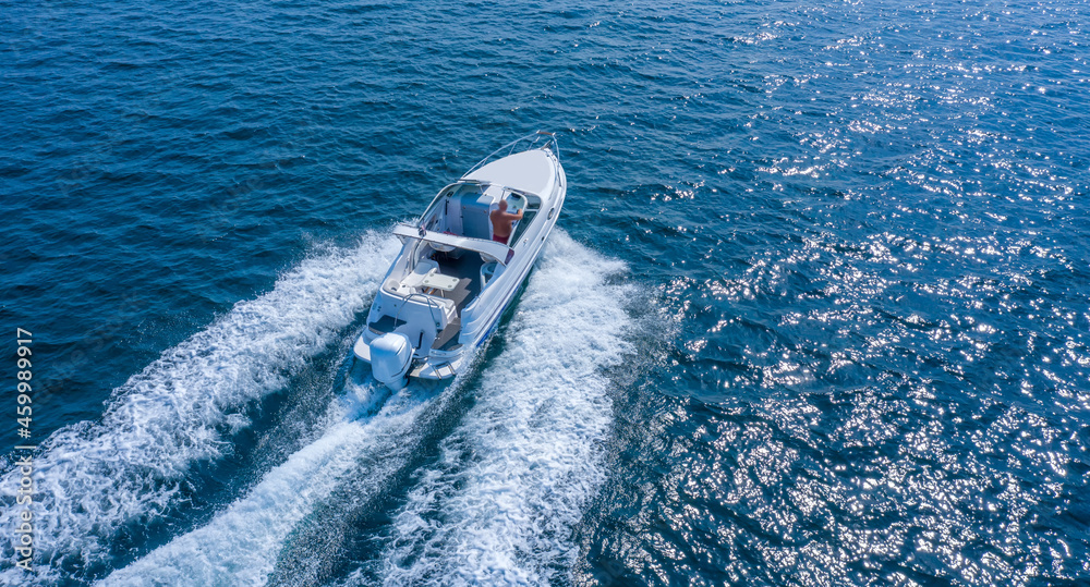 A high-speed boat or yacht maneuvers on the surface of the sea or ocean. Aerial view.