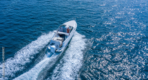 A high-speed boat or yacht maneuvers on the surface of the sea or ocean. Aerial view. © maykal