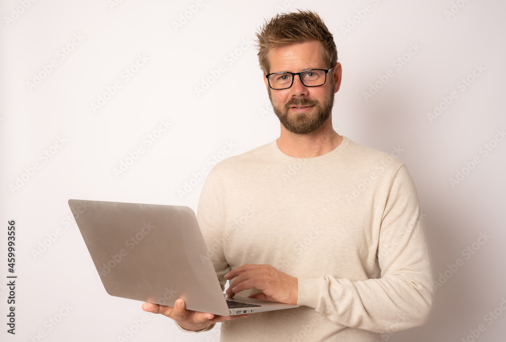 Studio portrait of a young smiling guy in a casual sweater with a laptop on a white background Studio portrait of a young smiling guy in a casual sweater with a laptop on a white background