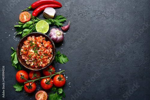 Tomato salsa (salsa roja) - traditional mexican sauce  with ingredients for making .Top view with copy space.