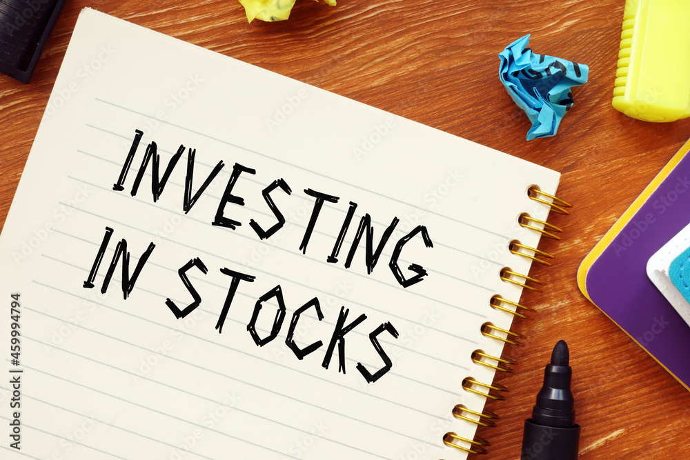 Naklejka premium Financial concept about INVESTING IN STOCKS question marks with phrase on the sheet.
