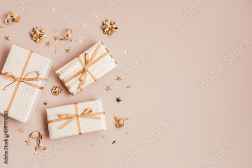 Christmas background with gift boxes wrapped in golden colored paper. Xristmas celebration, preparation for winter holidays. Festive mockup, top view, flat lay