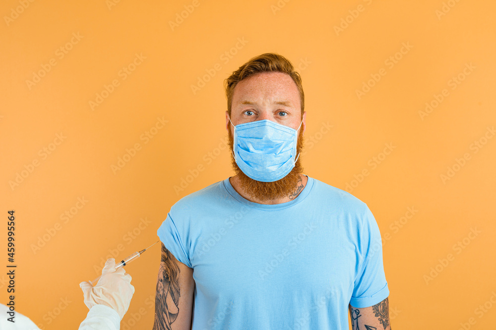 Serious man with beard, tattoo and mask for covid-19 is ready for the virus vaccine Serious man with beard, tattoo and mask for covid-19 is ready for the virus vaccine