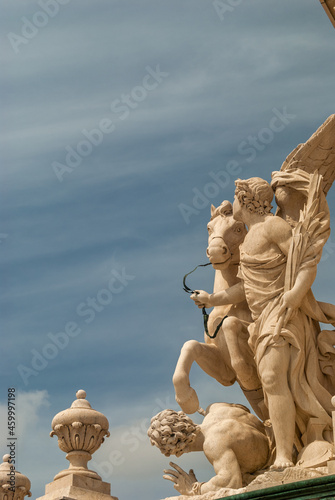 Lisbon, Portugal - April 8, 2021: Sculpture composition of an angel holding the reins of a horse and a man lying under the hooves with dramatic cloudy sky in the background