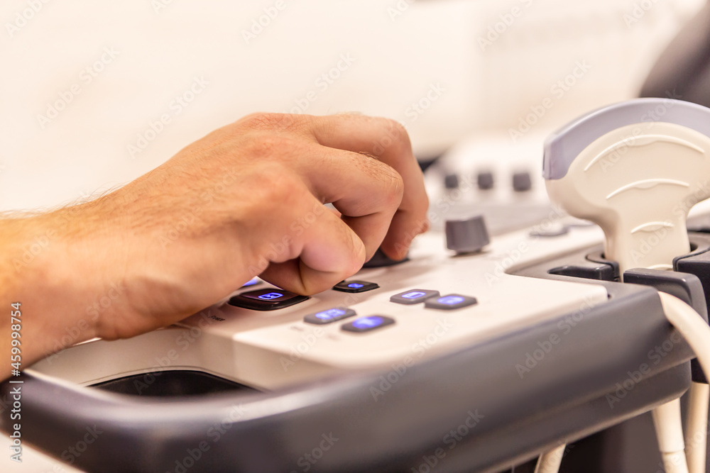 Fokus on a doctor´s hand handling the ultra sonic machine during an examination Fokus on a doctor´s hand handling the ultra sonic machine during an examination