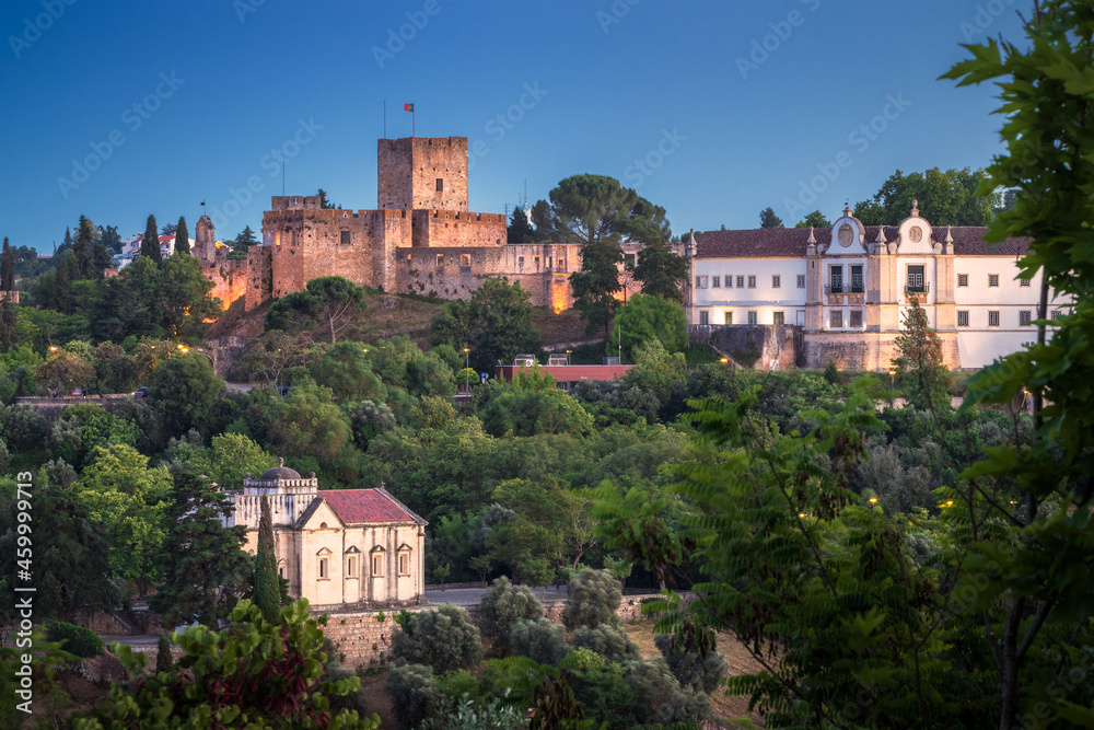 View at dusk of the castle of Tomar with the Convent of Christ on the side and the Chapel of Nossa Senhora da Conceição below, in Tomar, Portugal.