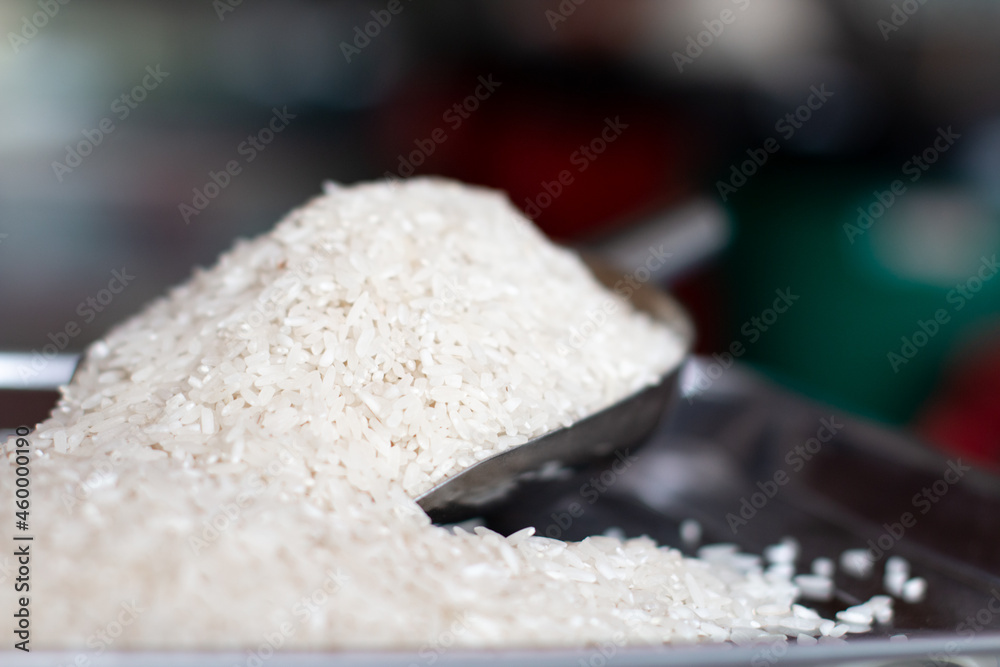 Spoon of white rice on a weighing scale. Grains of rice in detail. Food and vegetable advertising concept. Metal spoon for grains Spoon of white rice on a weighing scale. Grains of rice in detail. Food and vegetable advertising concept. Metal spoon for grains