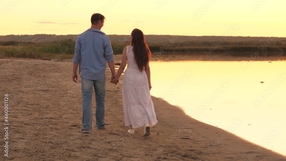 a man and a woman walk along the shore of the beach at sunset in the sky, romantic relationship of two people, happy family, cheerful people like to communicate, spend a carefree weekend together