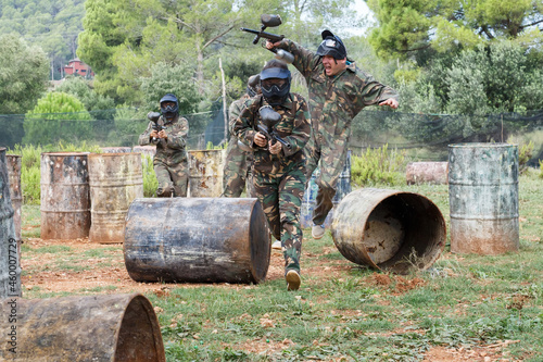 Dynamic paintball battle outdoors. Group of players in camouflage attacking opposite team