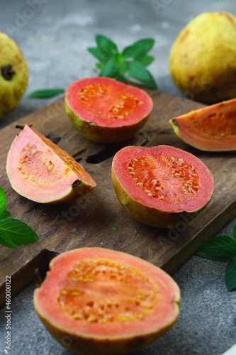 Guava fruit or Psidium Guava on wooden chopping board , on grey grainy background. 