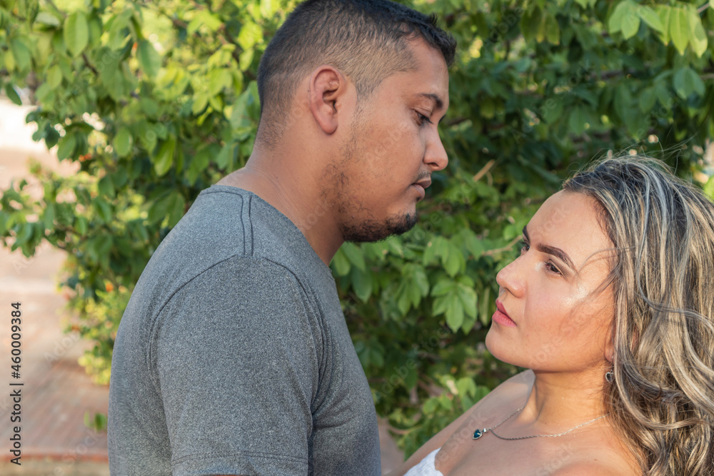 Hispanic Couple On A Tree Looking At Each Other Outdoors
