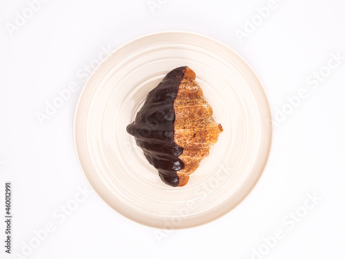 top angle of fresh croissant covered chocolate and topping with chocolate powder on a pastel plate placed on white table top. food concept on photography image.