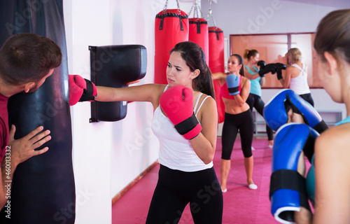 Portrait of sporty female boxer who is training with punching bag in fitness club © JackF