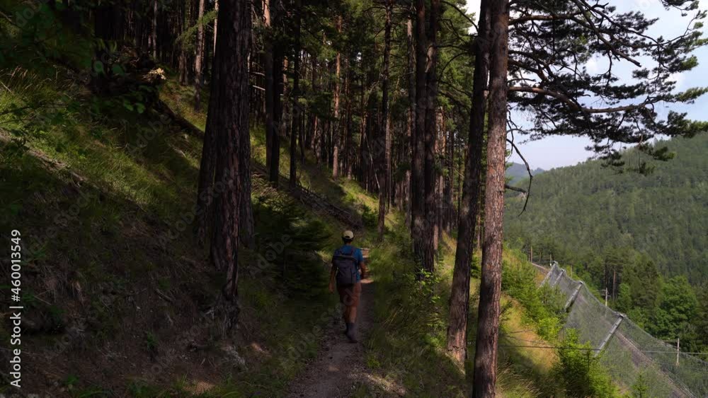 Back of male hiker walking on hiking path with safety nets Back of male hiker walking on hiking path with safety nets
