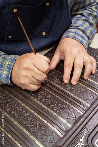 Bookbinder makes a unique cover for book. Handmake leather bookcover.  photo