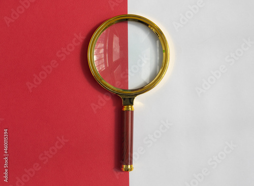 Golden magnifying glass over red and white background. Search tool. SEO concept.