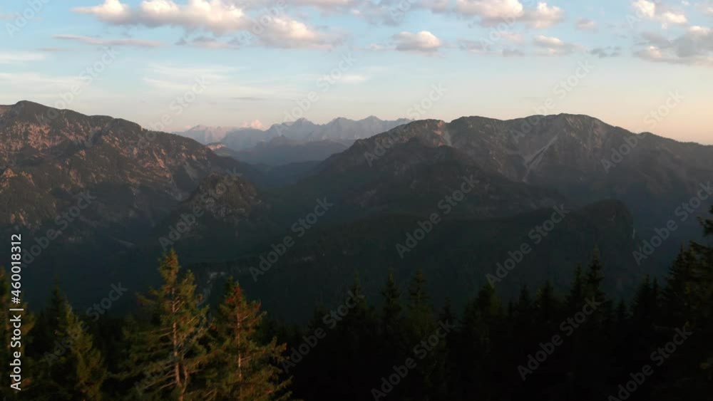 Aerial drone view low over sunlit forest a valley between mountains, in Unternberg alps, sunset in Austria Aerial drone view low over sunlit forest a valley between mountains, in Unternberg alps, sunset in Austria