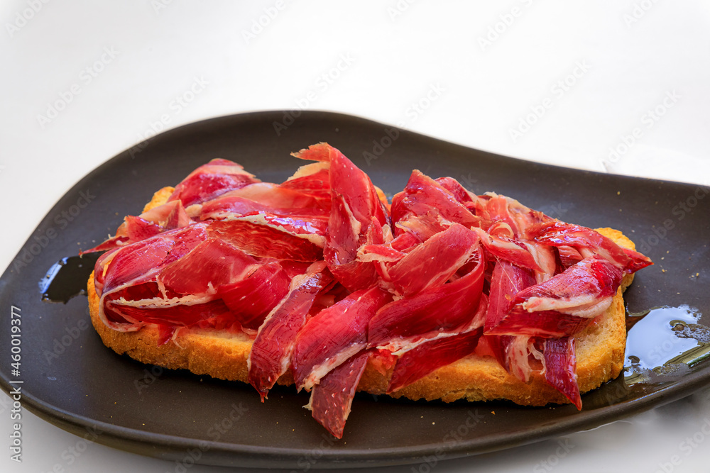 Serrano iberico ham sandwiches or bocadillo held on a wooden platter at a local shop in the old town or Casco Viejo of Pamplona, Spain Serrano iberico ham sandwiches or bocadillo held on a wooden platter at a local shop in the old town or Casco Viejo of Pamplona, Spain