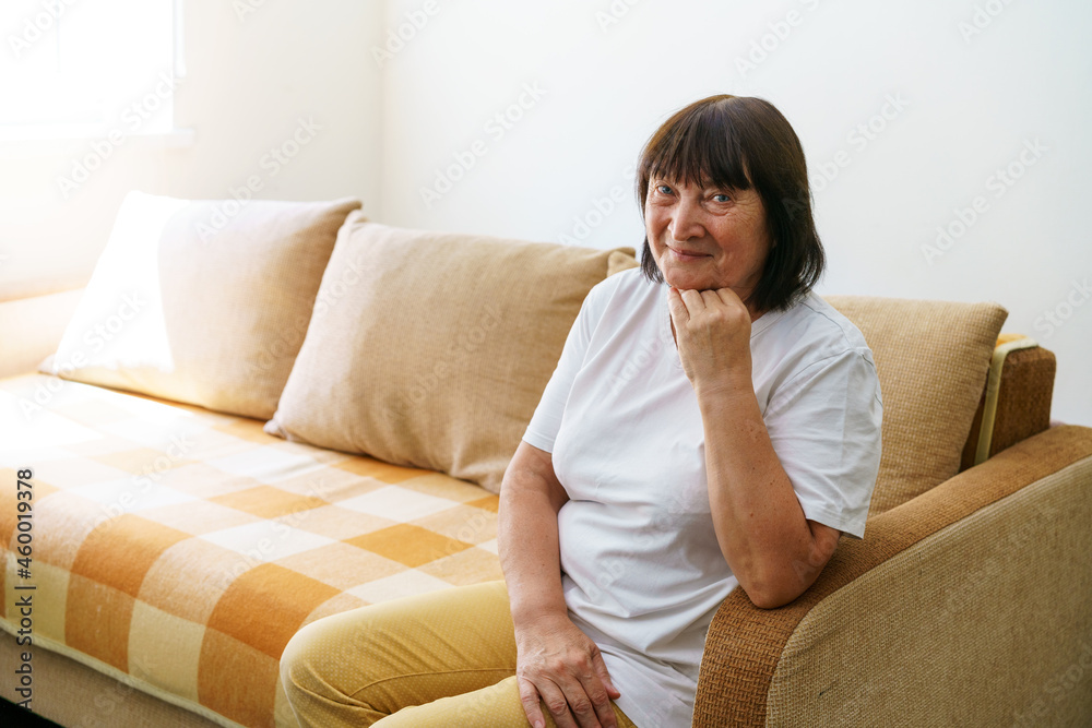 Portrait shot in head of peaceful calm middle aged woman relaxing on cozy sofa alone at home. Nice happy 60s old mature grandmother relaxing on living room couch posing for photo. Portrait shot in head of peaceful calm middle aged woman relaxing on cozy sofa alone at home. Nice happy 60s old mature grandmother relaxing on living room couch posing for photo.