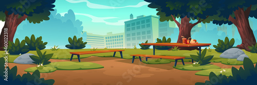 City park with wooden picnic table and benches, green trees, grass with flowers and town buildings on skyline. Vector cartoon summer landscape of empty public garden with food and drink on table