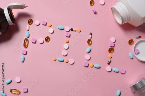 Assorted medicine pills on pink background.