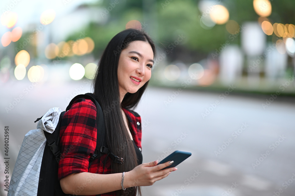 Smiling Asian woman traveller using application of taxi service app on smart phone.