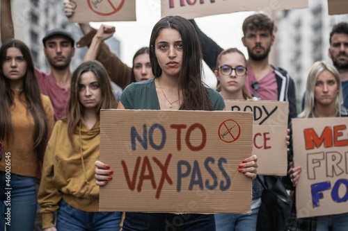 Group of Young people marching with signs with novax slogans photo