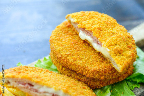 
 Crispy  deep fried home made     chicken Cordon bleu with cheese   and ham  and french fries on wooden rustic background.   photo