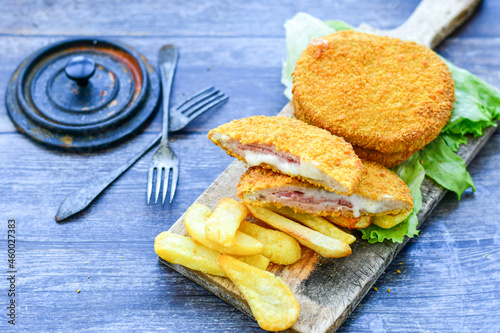 Photos Crispy  deep fried home made     chicken Cordon bleu with cheese   and ham  and french fries on wooden rustic background