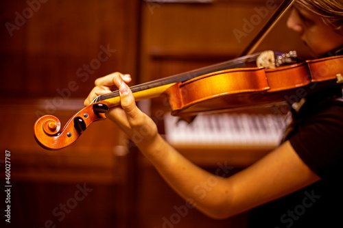 young violinist plays music on the violin with his back near the piano, horizontal
