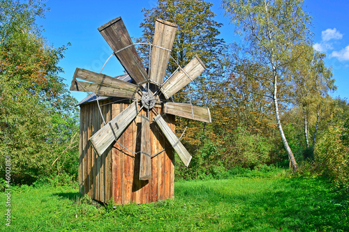  Old wooden windmill on the field against blue sky, ethnographic park Nowy Sacz, Poland Concept art, traditional craft and alternative production, environmental conservation, history.