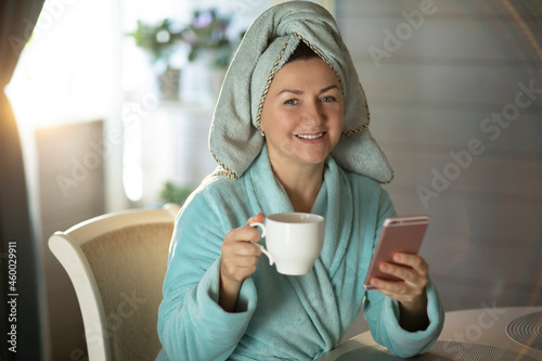 woman after shower in the morning, with a mug of coffee and a telephone