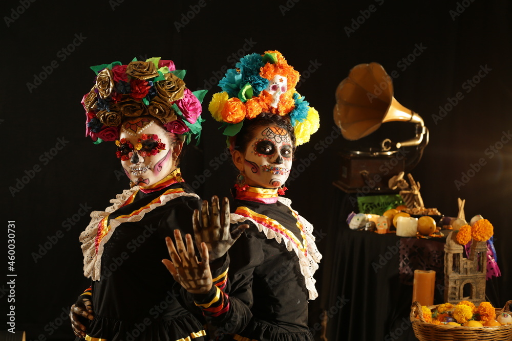 people dressed in Mexican folkloric black and very colorful costumes, with ornaments referring to the Day of the Dead, skull make-up people dressed in Mexican folkloric black and very colorful costumes, with ornaments referring to the Day of the Dead, skull make-up