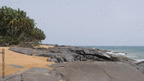 Waves crashing onto rocks next to palm trees on beautiful and remote Sunset Beach near Buchanan, Liberia. photo