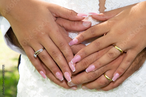 wedding fingers golden rings on bride groom hands on white dress background