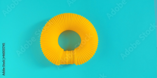 Pop tube. Yellow anti stress sensory plastic toy for children on blue background. Fidget corrugated poptube. Top view  flat lay  copy space.