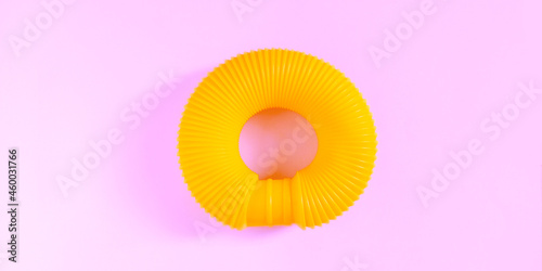 Pop tube. Yellow anti stress sensory plastic toy for children on pink background. Fidget corrugated poptube. Trend of 2021. Top view  flat lay  copy space.