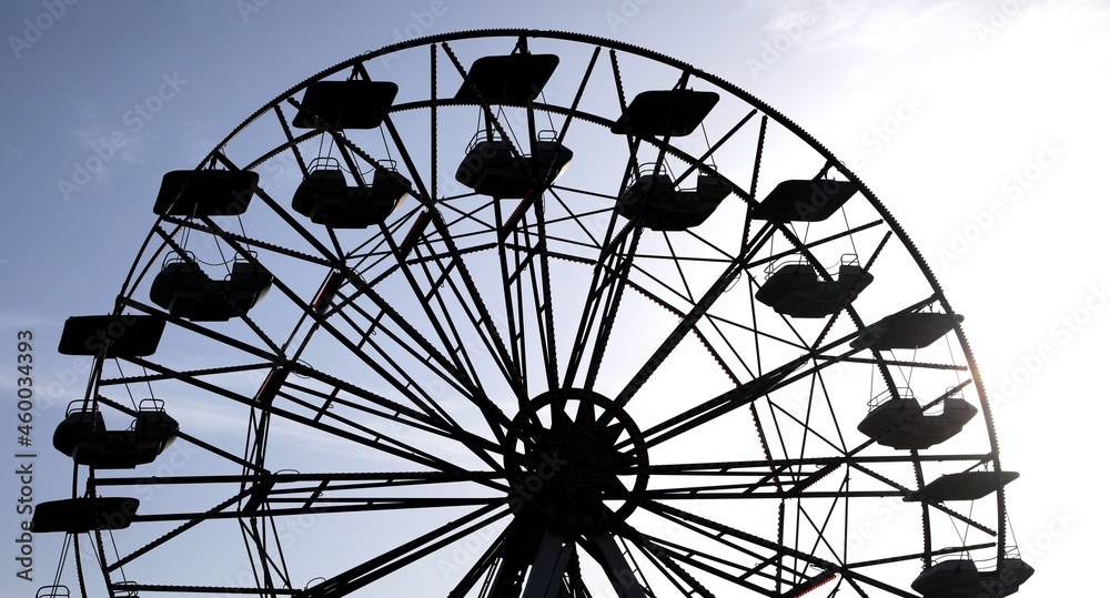 silhouette of the ferris wheel with backlit baskets in an amusement park silhouette of the ferris wheel with backlit baskets in an amusement park