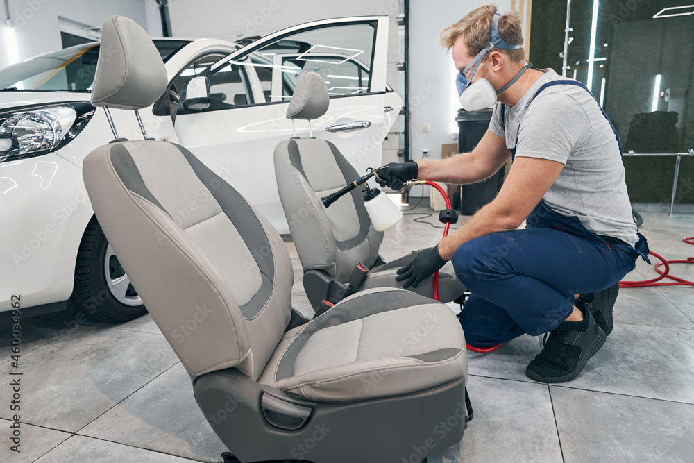 Car service worker doing chemical cleaning of seats. Detailing