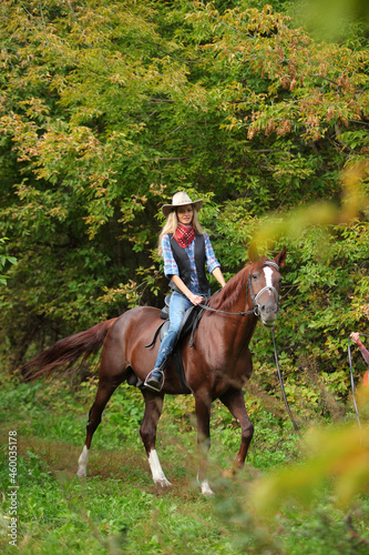 Beautiful cowgirl ride her horse in autumn country road at sunset © horsemen
