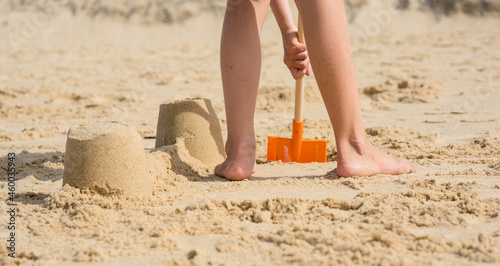 portrait of a pretty little girl making sand blocks on a sunny beach