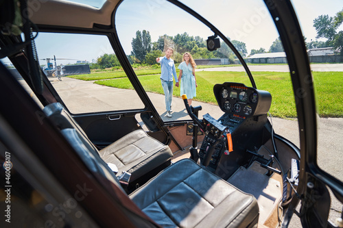 Joyful guy showing his private helicopter to smiling woman